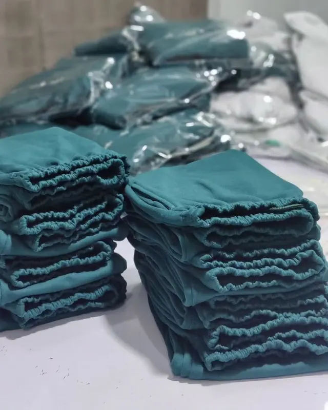 Stacks of folded teal garments in polybags, packed for a bulk order, Wears For You, Sialkot Pakistan