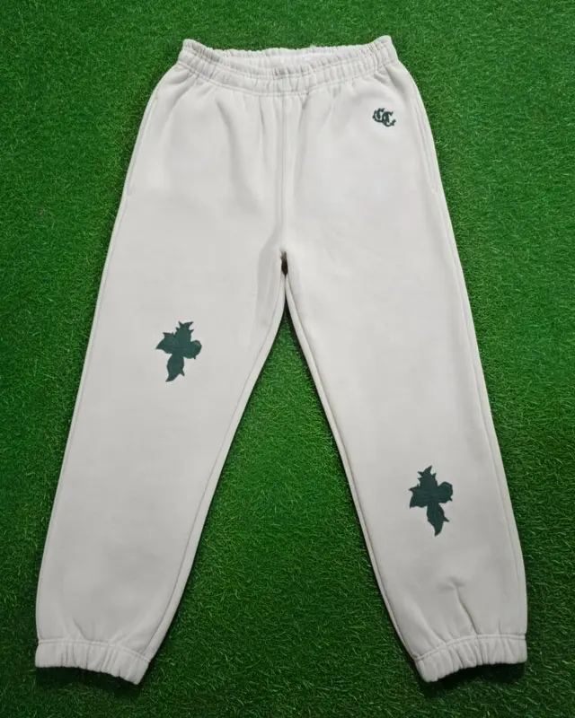 Off-white joggers with green cross embroidery on the factory turf backdrop, Wears For You, Sialkot Pakistan