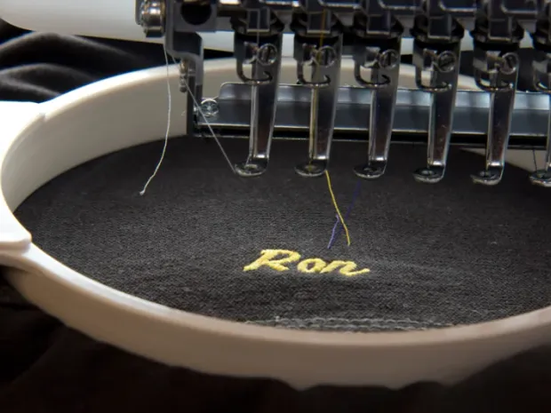 Embroidery machine stitching a custom logo onto a garment, custom embroidery, Wears For You, Sialkot Pakistan