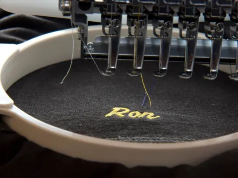 Embroidery machine stitching a custom logo onto a garment, custom embroidery, Wears For You, Sialkot Pakistan